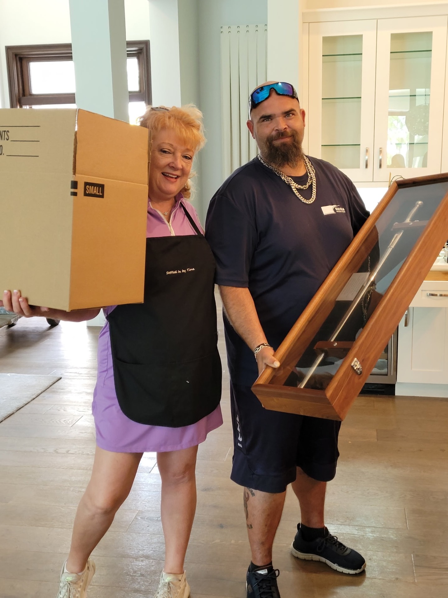 Tina and a Settled In by Tina crew member carrying a client's box and framed artwork