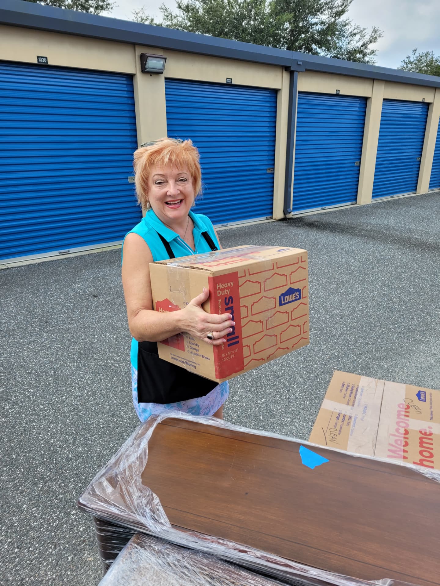 Tina carrying a labeled box outside a storage unit